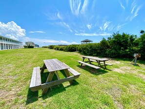 Un espacio al aire libre con césped, mesas de picnic y un pabellón al fondo.