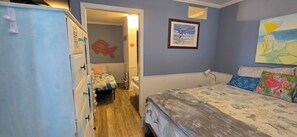 Un dormitorio con cama, cómoda, silla, pared decorada con un pez y un cuadro.