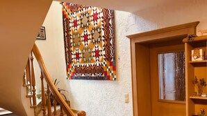 Eine Treppe mit hölzernen Geländern, einem gemusterten Wandbehang und einer Holztür mit Fenster.