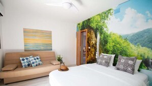 Un dormitorio con cama, sofá, un cuadro y un mural de un bosque.