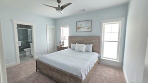A bedroom with a wooden bed, a ceiling fan, and a large window.