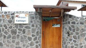 A stone wall with a wooden door and a sign reading "Galapagos Cottages".