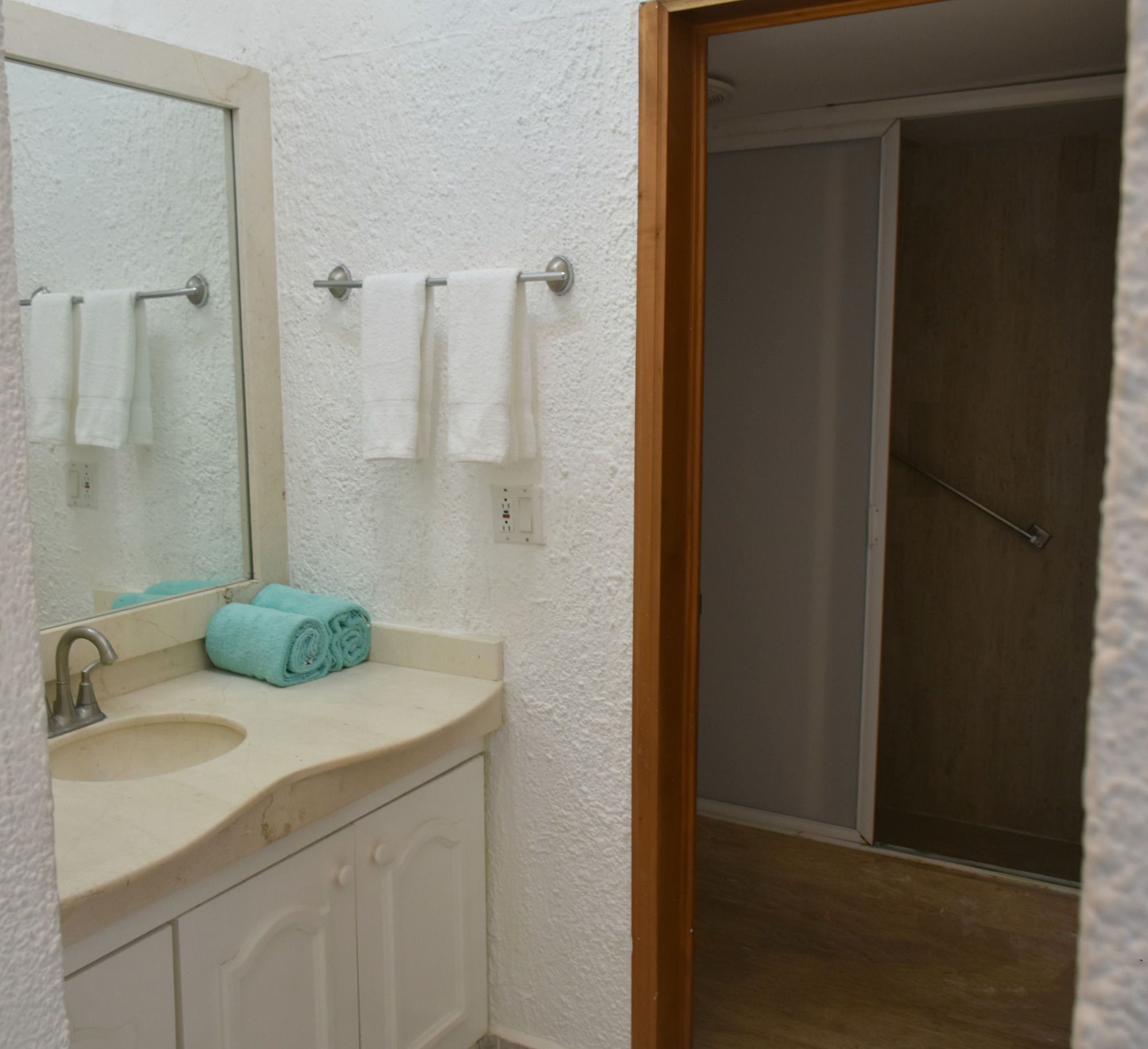 A bathroom with a sink, mirror, and towel rack.