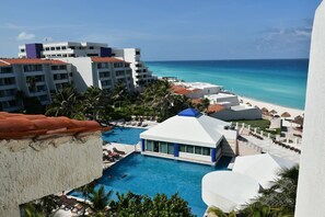 A resort with a swimming pool, beach, and ocean view. - Seaside Condo by Solymar (Cancun)