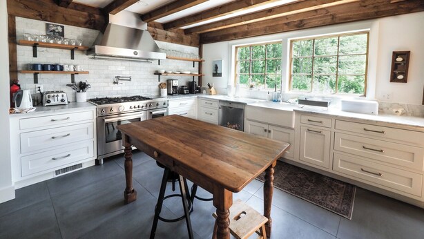 Una cocina moderna con armarios blancos, una mesa de madera y un gran ventanal con vistas al exterior.