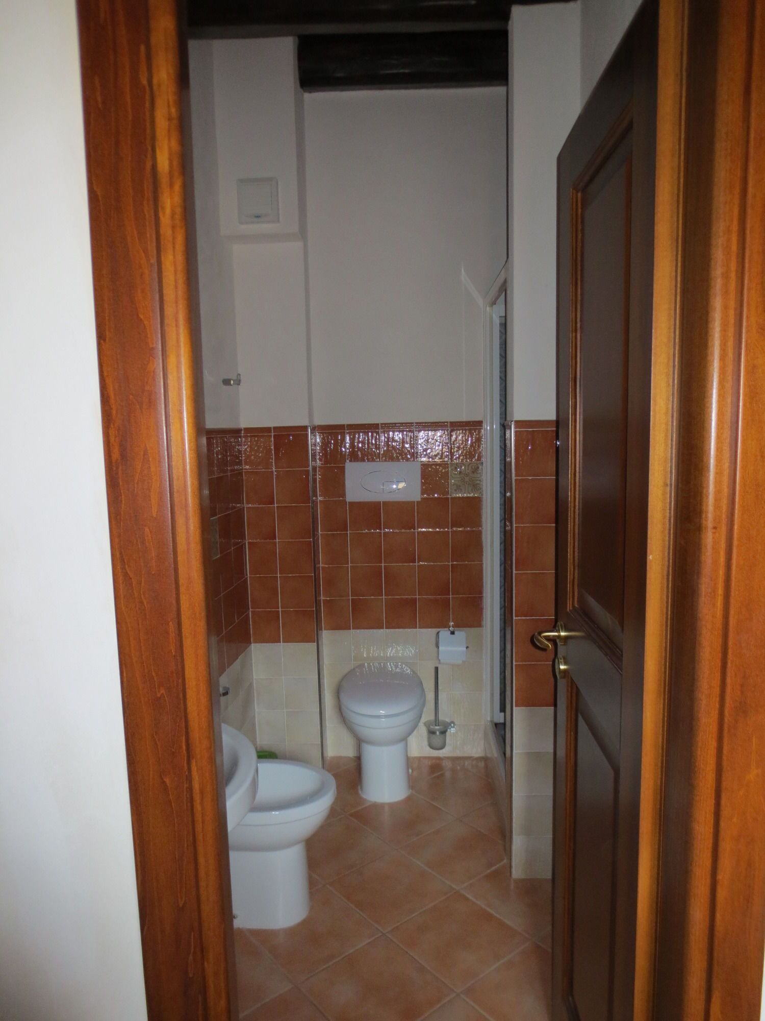 Une petite salle de bain avec deux toilettes, un lavabo et une douche.