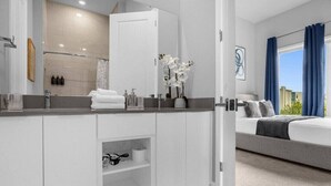 Una habitación de hotel moderna con una cama grande, un baño con tocador y vistas a la ciudad.