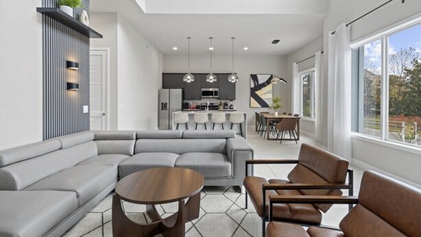 A modern living room with a sectional sofa, a round coffee table, and a dining area with a table and chairs.