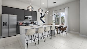 A modern kitchen with a central island, stainless steel appliances, and pendant lighting.