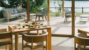 A dining area with a table set for breakfast, overlooking a body of water. - Hotel & Lakehouse Soka (Kyotango)