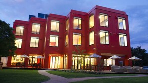 A multi-story building with a red facade, large windows, and outdoor seating areas. - Hotel & Lakehouse Soka (Kyotango)