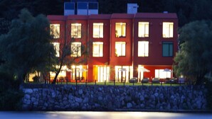 A multi-story building with a stone wall in front, situated by a body of water. - Hotel & Lakehouse Soka (Kyotango)
