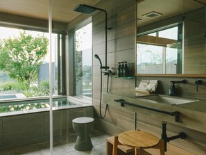 A modern bathroom with a glass shower enclosure, a toilet, a sink with a mirror, and a small wooden stool. - Hotel & Lakehouse Soka (Kyotango)