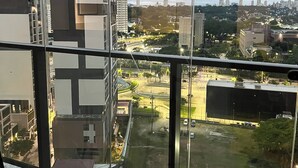 A high-rise building with a view of a cityscape, including various buildings and a park area. - Studio sofisticado 230m do metrô (São Paulo)
