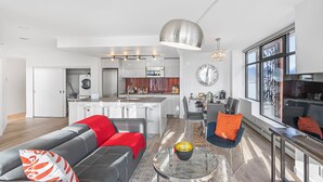 Ein modernes Wohnzimmer mit Ledersofa, einem Glastisch und einem Essbereich mit Bar.