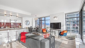 Eine moderne Küche mit einer großen Kochinsel, einem Essbereich mit Stühlen und einem Wohnzimmer mit Sofa und Sesseln.