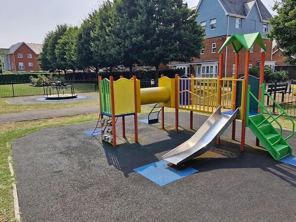 A playground with a slide, climbing structures, and a fenced area.