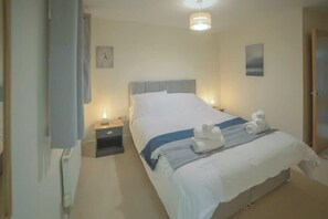 Una camera d'albergo con un letto, comodini, una lampada da comodino, una sveglia a muro e un lampadario al soffitto.