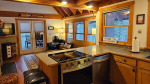 A cozy kitchen with wooden cabinets, a stove, and a dining area with a bench.