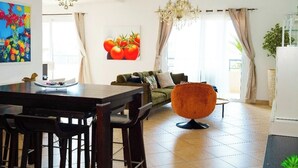 Una sala moderna con comedor, un sofá, un sillón redondo naranja y una araña.