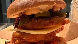 A sandwich with multiple layers including a bun, lettuce, tomato, and various fried items. - Cozy Affordable Place in Great Yarmouth (Great Yarmouth)