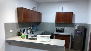 Uma cozinha compacta com ilha central, micro-ondas, geladeira e armários de madeira.