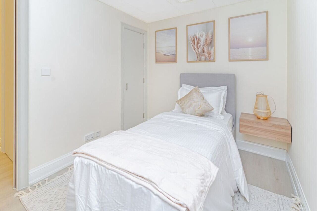 Une chambre à coucher avec un lit, une table de chevet et une commode. Trois tableaux encadrés sont accrochés au mur au-dessus du lit.
