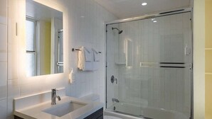 A modern bathroom with a glass-enclosed shower, a large mirror, and a white sink. - Super 8 hotel room near Union Square and Moscone Convention Center (San Francisco)