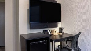 A hotel room with a flat-screen TV mounted on the wall, a small desk with a coffee maker, a phone, and a compact dishwasher. - Super 8 hotel room near Union Square and Moscone Convention Center (San Francisco)