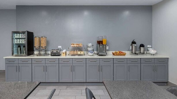A modern kitchen with grey cabinets, a built-in coffee machine, and a variety of appliances and food items on the counter. - Super 8 hotel room near Union Square and Moscone Convention Center (San Francisco)
