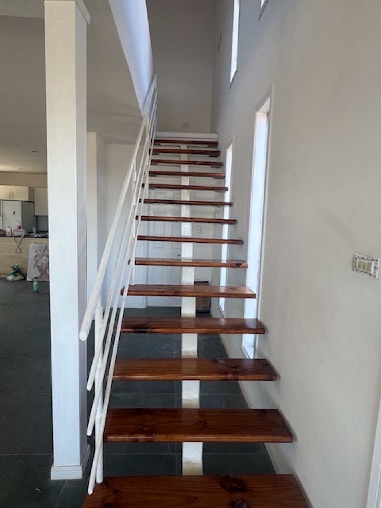 A staircase with wooden steps and white railings, leading to a landing with a door.