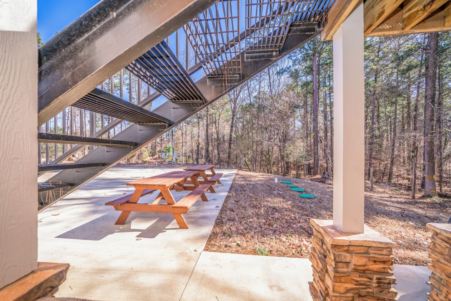 A covered outdoor area with picnic tables and a staircase leading to a higher level.
