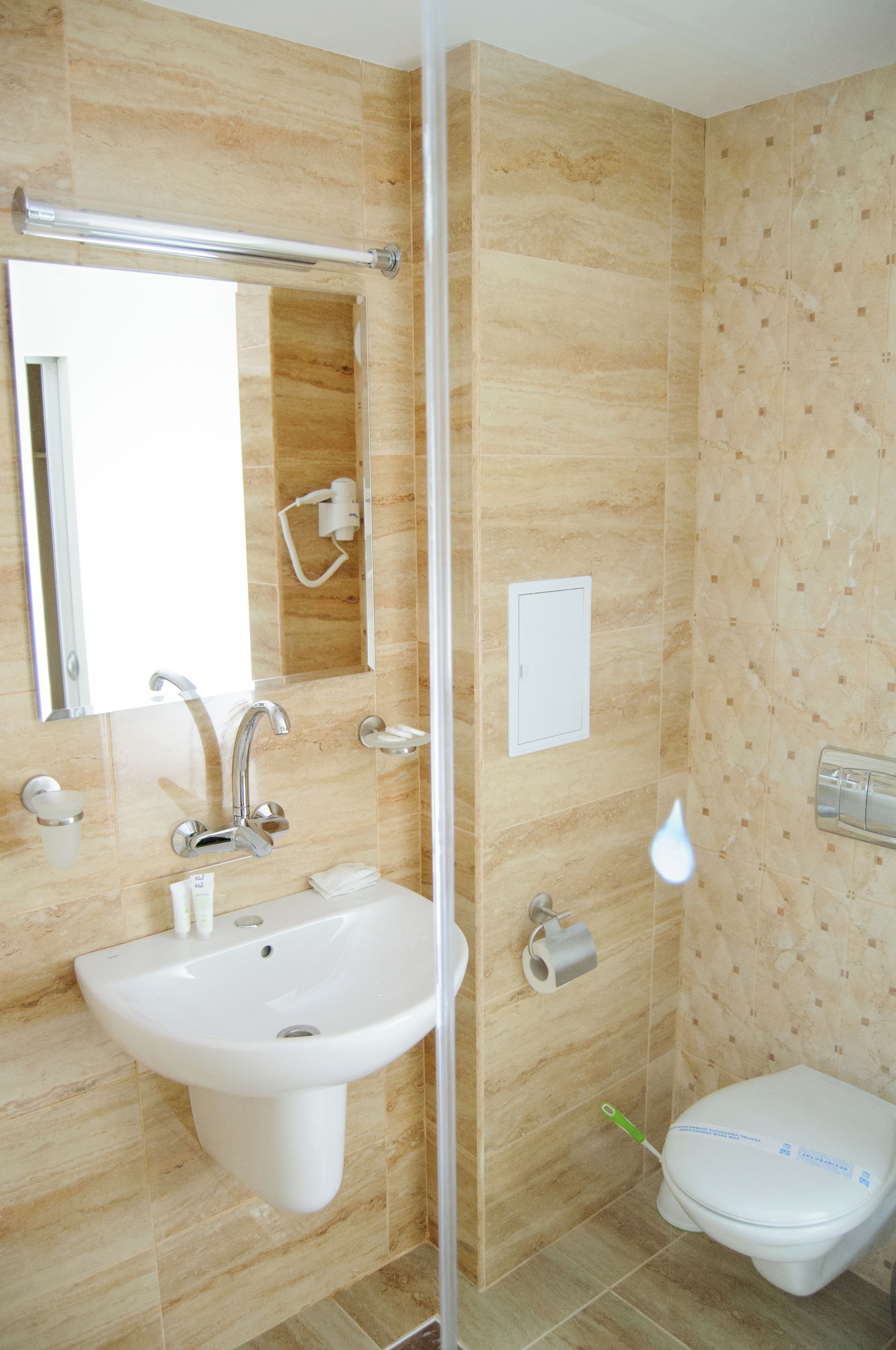A bathroom with a sink, mirror, toilet, and shower.