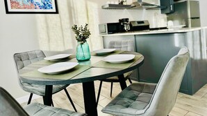A modern dining area with a round table, grey upholstered chairs, and a small vase with greenery.