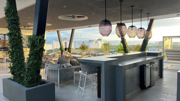 Eine moderne Außenküche mit Barbereich, Sitzgelegenheiten und Blick auf die Stadt.