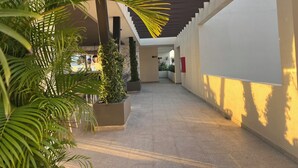 Ein überdachter Gang mit Fliesenboden, Blumentöpfen und einer Treppe.