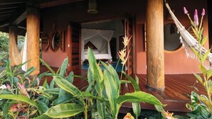 A wooden deck with a hammock, a bed with a white canopy, and a large mirror. - Trancoso. Alto do Segredo. 2 Suites.  5 minutes from the beach and 2 km from Quadrado (Trancoso)