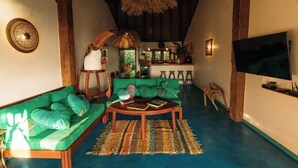 A spacious living area with a green sofa, a coffee table, and a TV. - Trancoso. Alto do Segredo. 2 Suites.  5 minutes from the beach and 2 km from Quadrado (Trancoso)