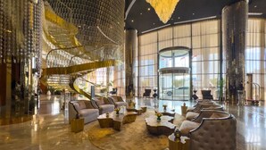 Eine großzügige Lobby mit einer imposanten Treppe, komfortablen Sitzgelegenheiten und einem geräumigen Glastauschaufzug.