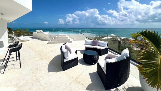 Une terrasse sur le toit, aménagée avec du mobilier d’extérieur, une piscine et une vue sur l’océan.