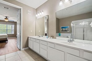 A modern bathroom with a large vanity, a double sink, and a walk-in shower. - Orlando Resort Rentals Near Universal (Orlando)
