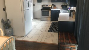A compact kitchen with a refrigerator, stove, oven, and dark cabinets.