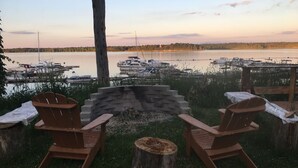 A lakeside seating area with Adirondack chairs and a stone fire pit.