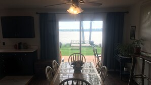 A dining area with a table and chairs, a ceiling fan, a view of a body of water, and a potted plant.