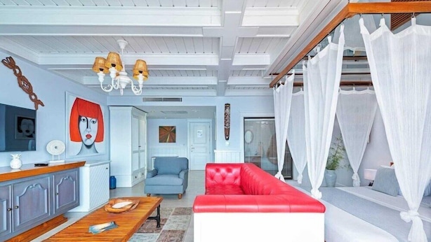 Un salon avec un canapé rouge, une table basse en bois, un téléviseur et un ventilateur de plafond.