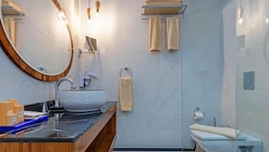 Une salle de bain moderne avec un meuble-lavabo en bois, un grand miroir ovale, une douche en verre et un sol en marbre.
