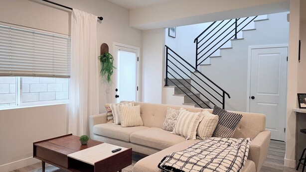 A modern living room with a sofa, a coffee table, and a staircase leading to an upper floor.