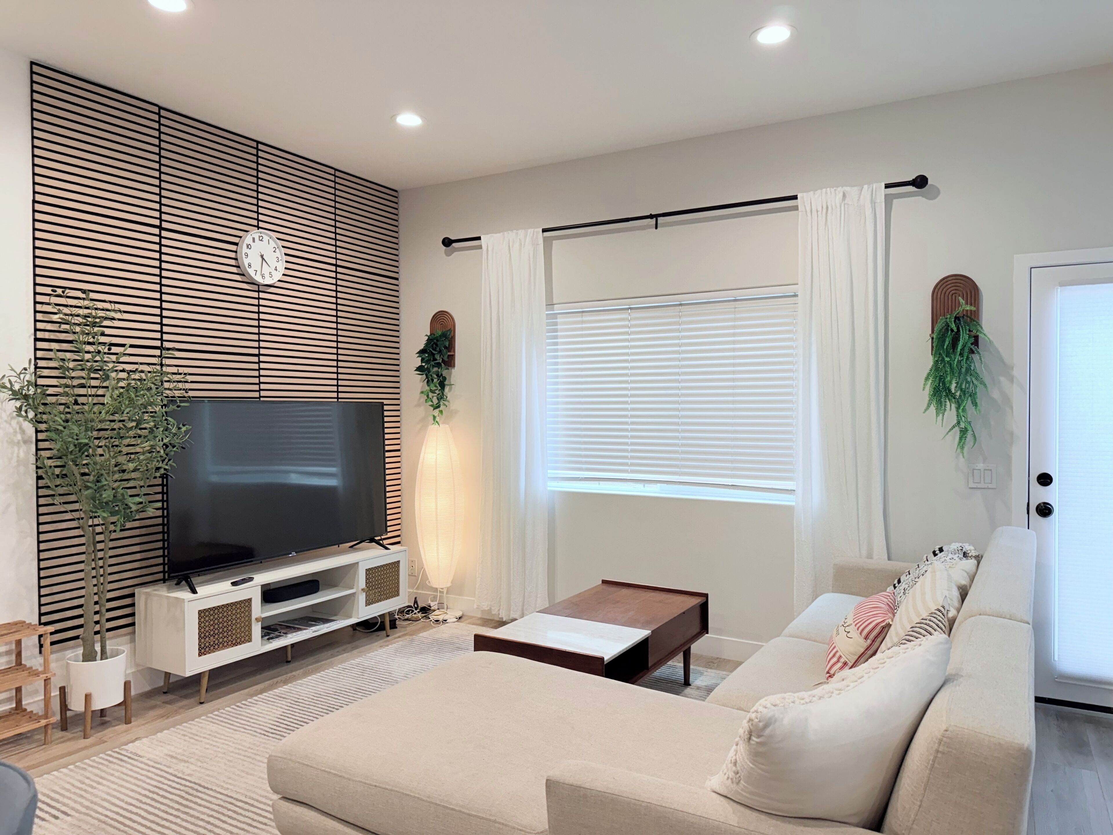 Una sala de estar moderna con un televisor de pantalla plana, un sofá, una mesa de centro y un mueble para la televisión.