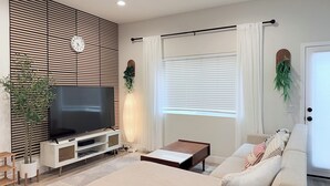A modern living room with a flat-screen TV, a sofa, a coffee table, and a TV stand.