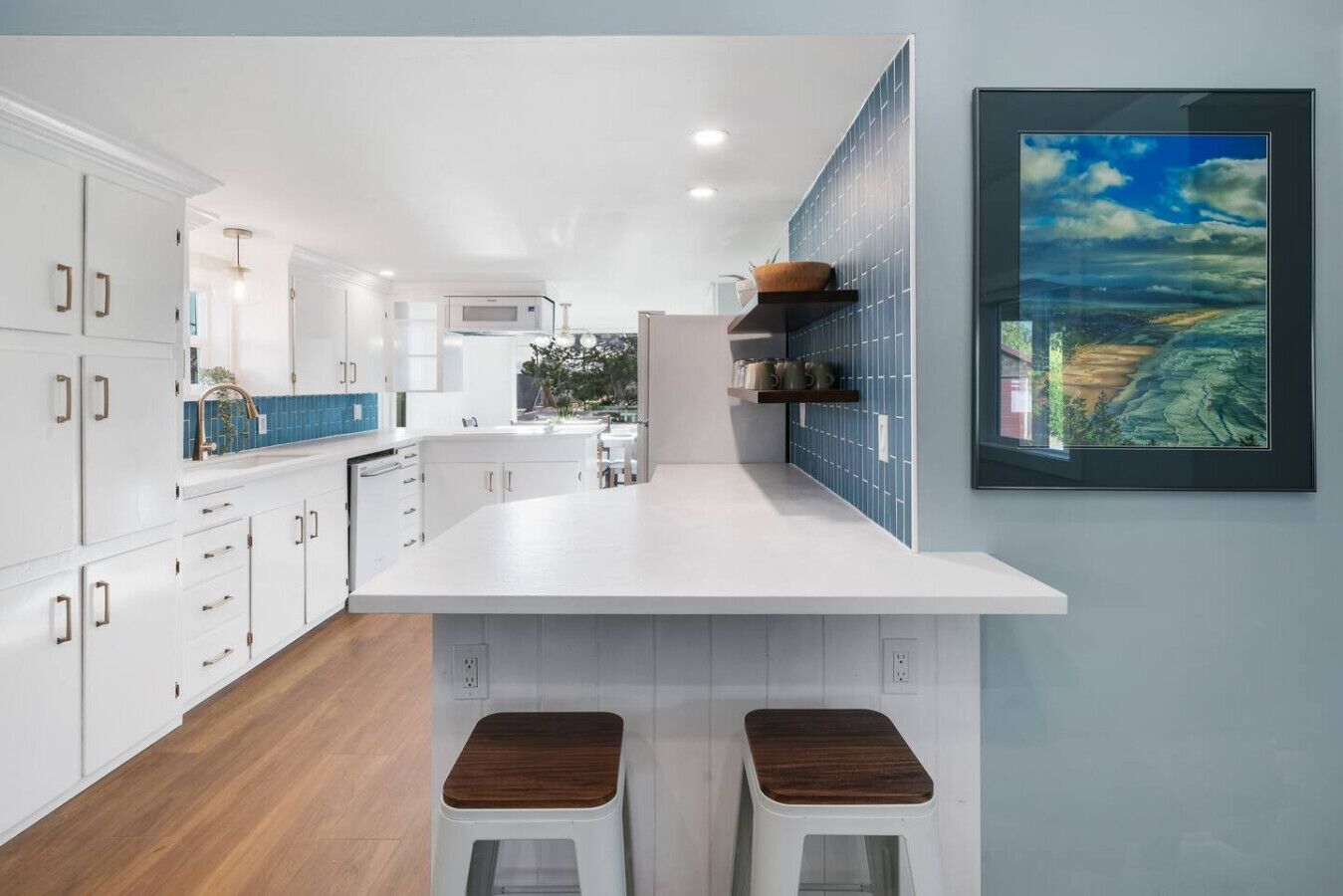 A modern kitchen with white cabinetry, a large island, and a blue backsplash.